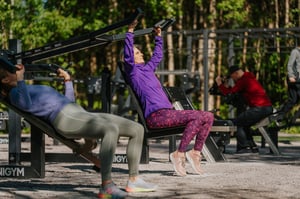 Utegym från Omnigym med justerbara vikter en solig dag, där tre personer tränar och använder olika maskiner