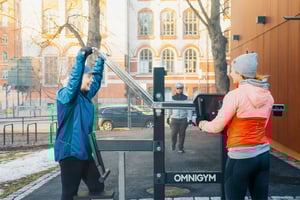 Two smiling women chatting at outdoor gym in Helsinki and cyclist arriving to the location